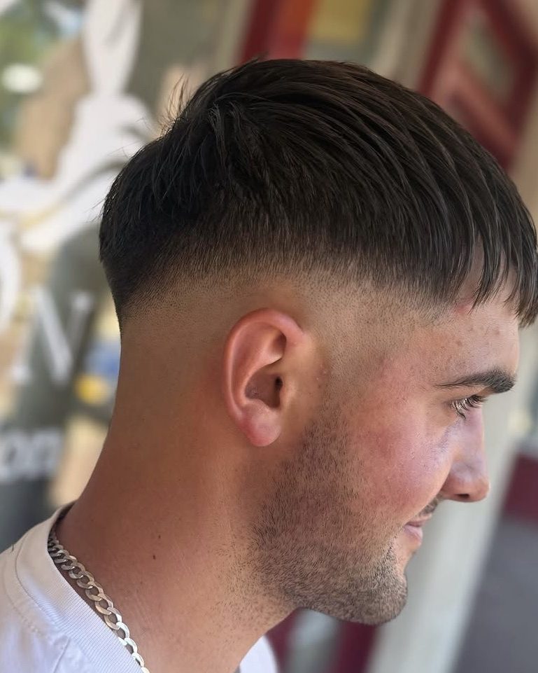 Korte herensnit met een strakke fade, van opzij